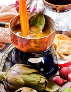 a small pot of bagna cauda with a candle burning underneath, plus fresh vegetables for dipping