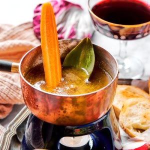 a small pot of bagna cauda with a candle burning underneath, plus fresh vegetables for dipping