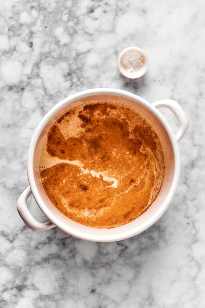 heating milk with spices in a white pot