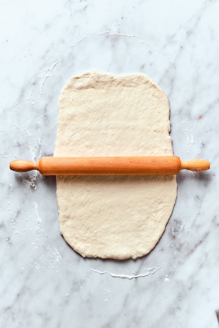 Rolling out pizza dough on marble work surface