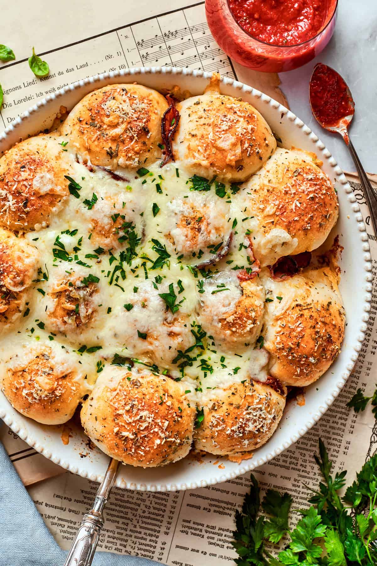 Homemade pizza bites tuck pepperoni and gooey mozzarella into seasoned pizza dough, then they're baked with even more cheese on top. Yum! overhead photo of pizza bites in a white baking dish