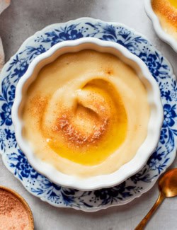 Norwegian rommegrot in a white bowl, with cinnamon-sugar and melted butter