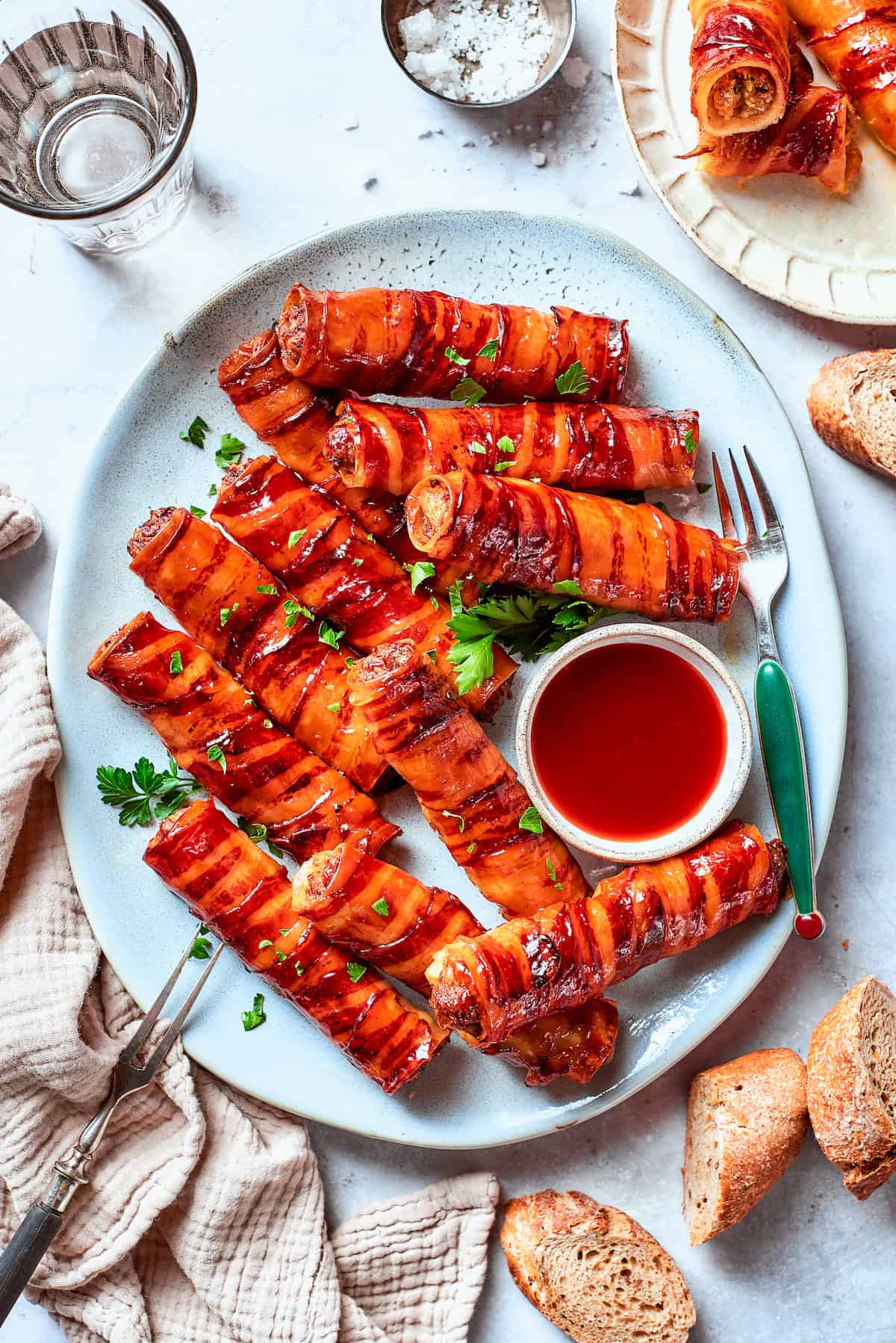 This baked shotgun shells recipe is a simpler version you can make in the oven — no smoker required! Smoky, savory, spicy and irresistible! Overhead view of shotgun shells with bowl of barbecue sauce for dipping