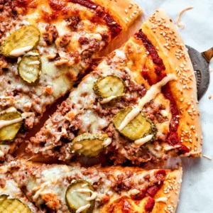 removing a slice of cheeseburger pizza from the whole pizza