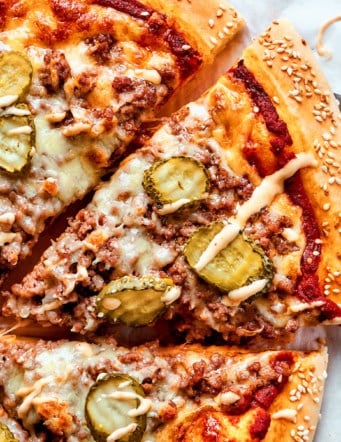 removing a slice of cheeseburger pizza from the whole pizza