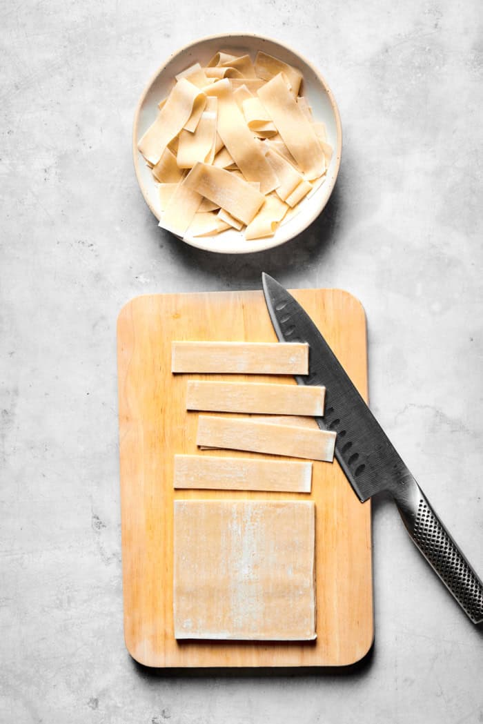 Overhead view of wonton wrappers being cut into strips
