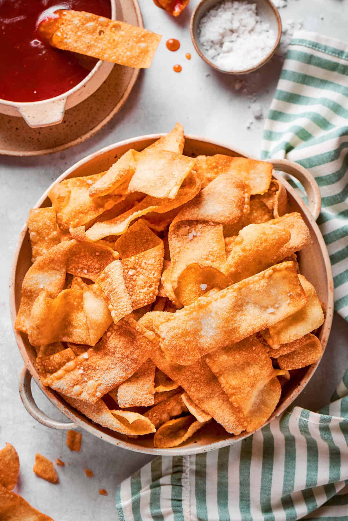 These easy homemade wonton chips have the most fantastic crunch and a salty flavor that makes them pair with just about anything! a bowl of homemade wonton chips with dipping sauce