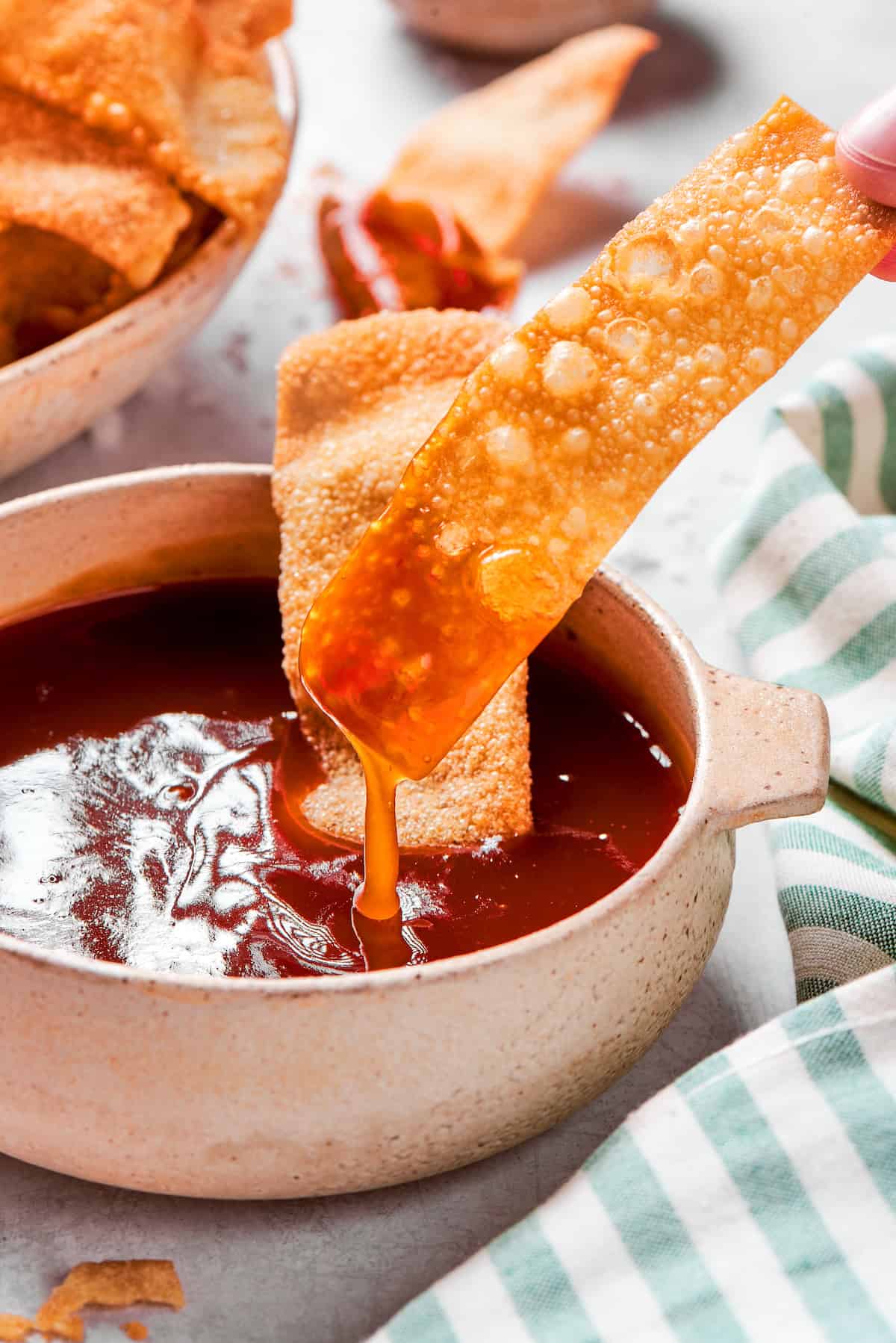 Dipping wonton chip into sweet and sour sauce