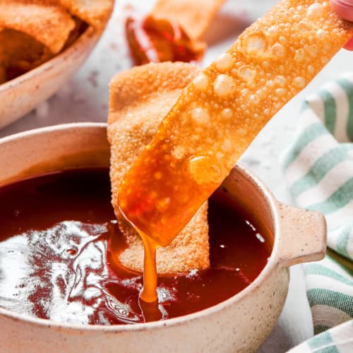 dipping a homemade wonton chip into sweet and sour sauce