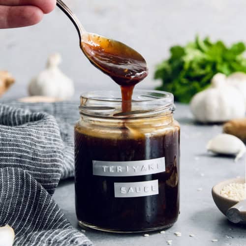 Drizzling homemade teriyaki sauce from spoon into jar