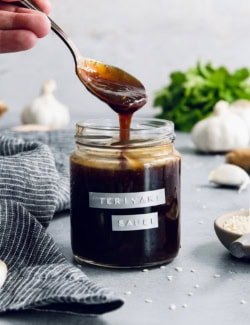 Drizzling homemade teriyaki sauce from spoon into jar