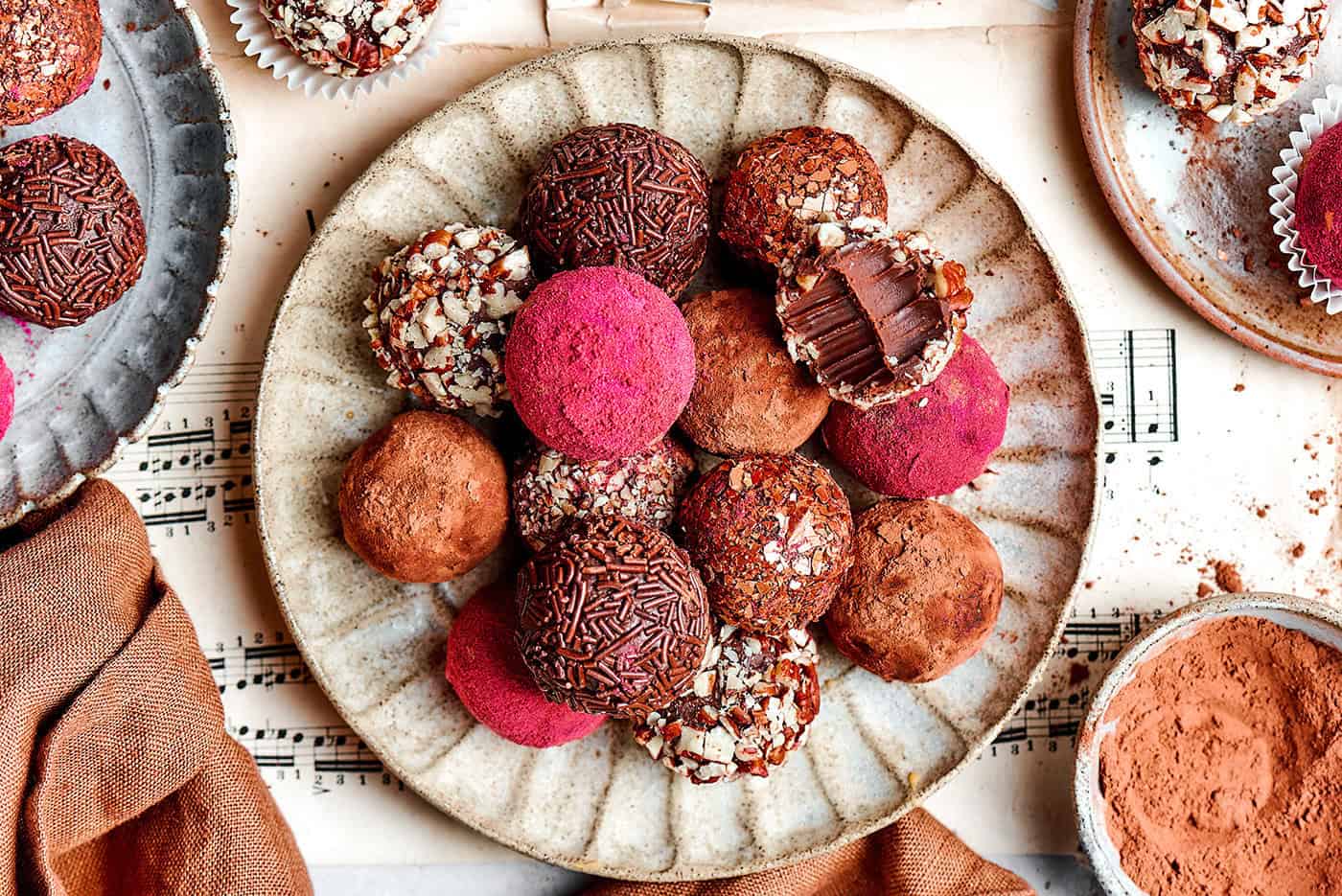 chocolate truffles rolled in a variety of coatings, on a cream colored plate