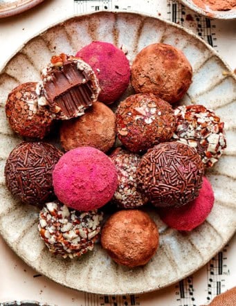 chocolate truffles rolled in a variety of coatings, on a cream colored plate