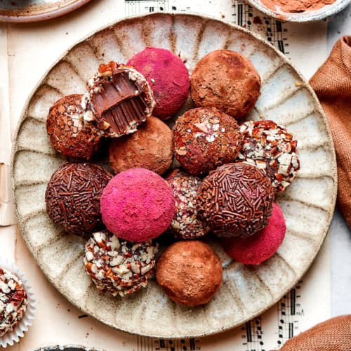chocolate truffles rolled in a variety of coatings, on a cream colored plate