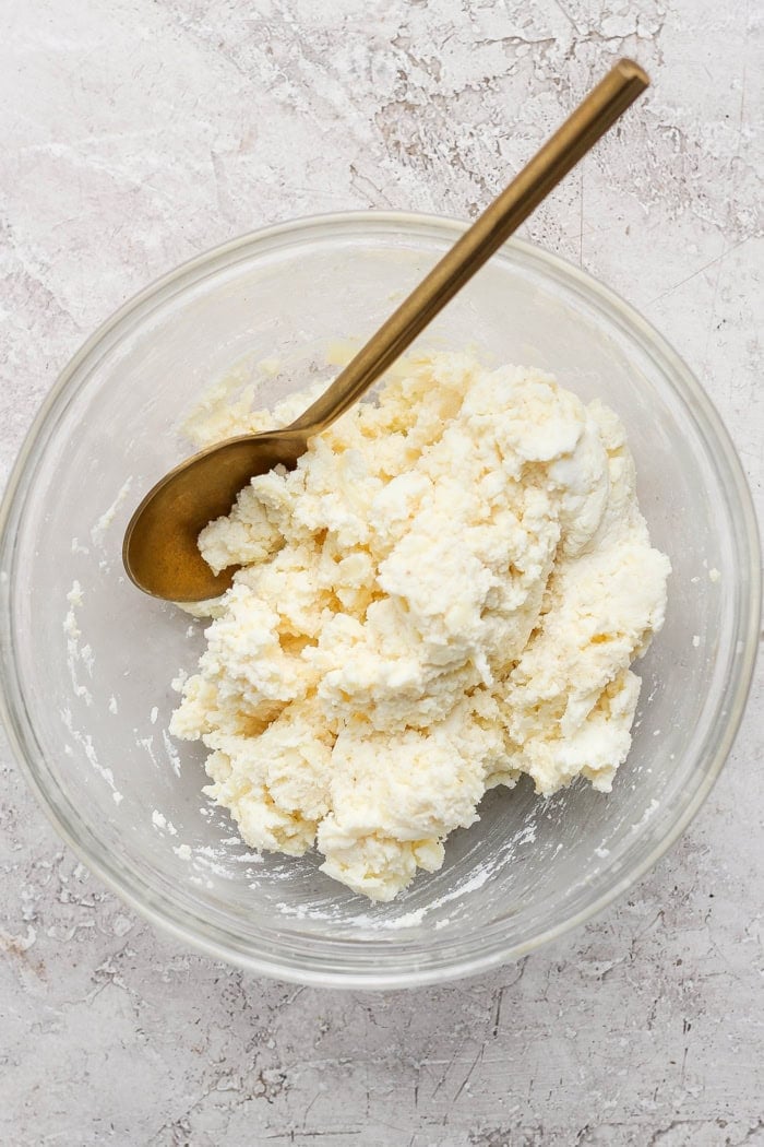 Bowl of ricotta cheese mixture in mixing bowl with spoon