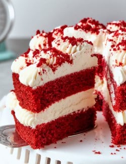 removing a piece of double layer red velvet cake with cream cheese frosting