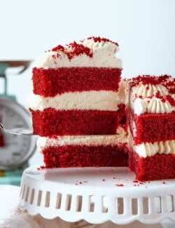 removing a piece of double layer red velvet cake with cream cheese frosting