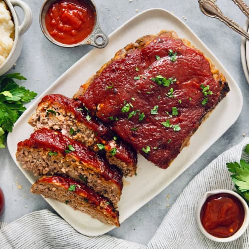 Overhead view of air fryer meatloaf on platter with three slices cut