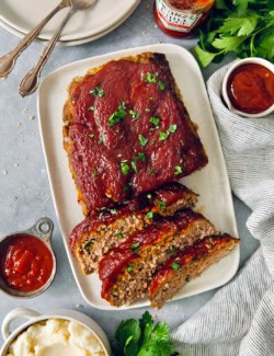 Overhead view of air fryer meatloaf on platter with three slices cut