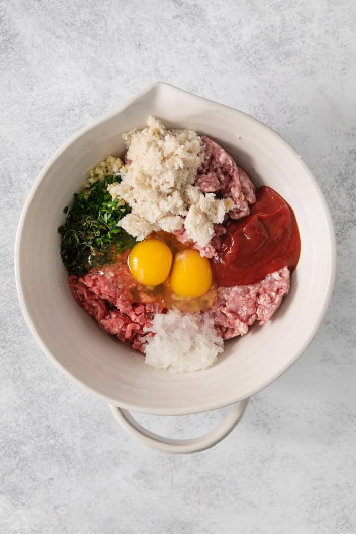 Overhead view of ingredients for meatloaf in bowl before mixing