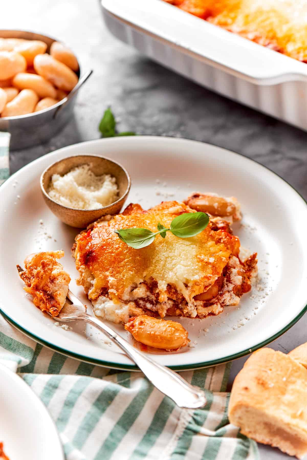 Lasagna beans on plate with fork and small bowl of Parmesan