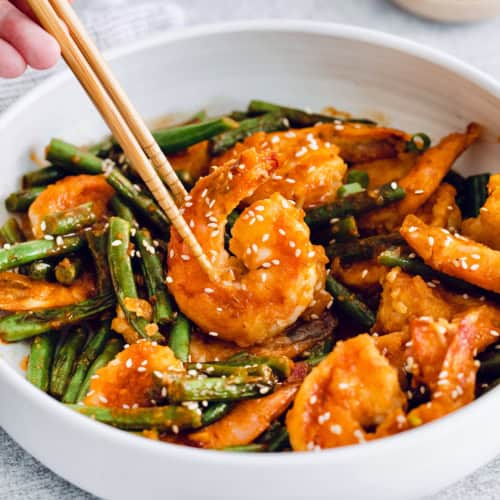 Chopsticks picking up Hunan shrimp from bowl