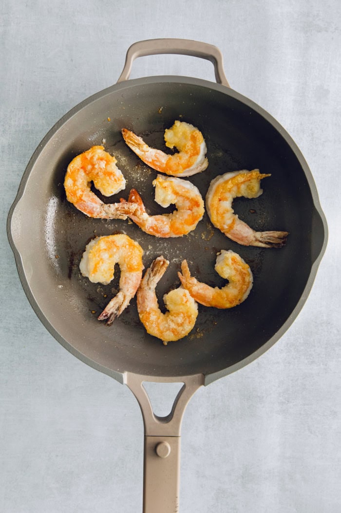 Overhead view of shrimp cooking in skillet