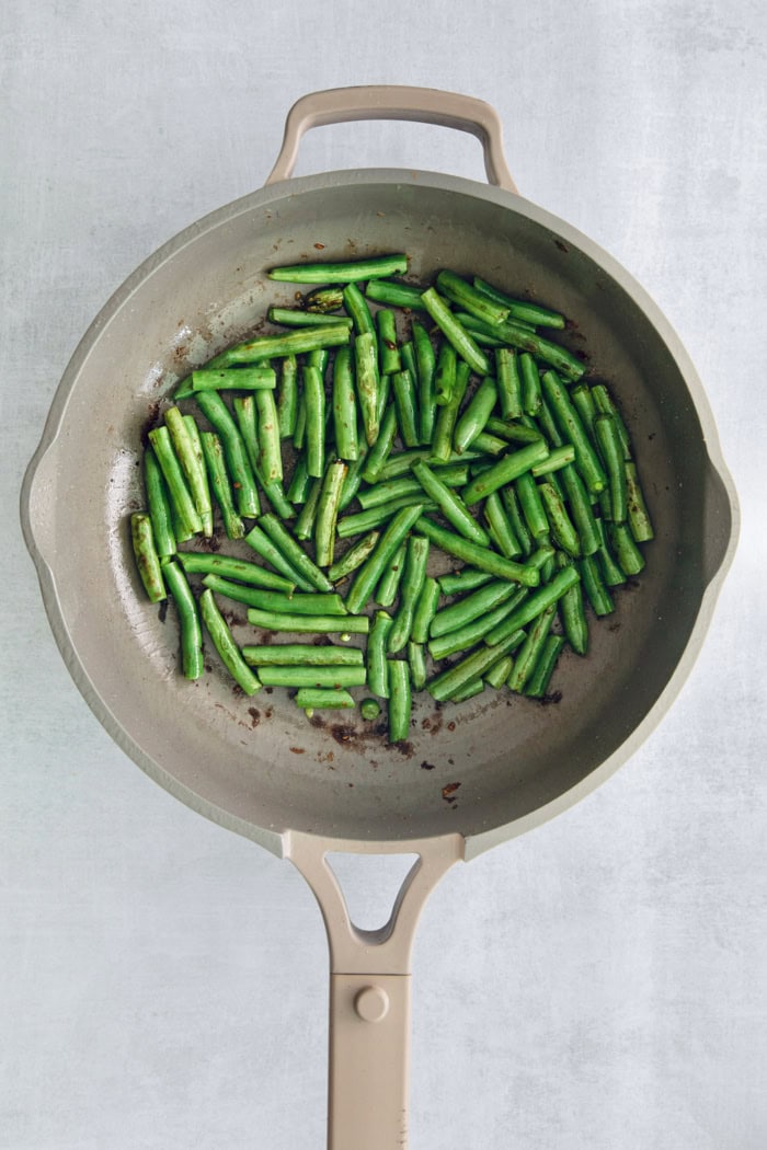 Overhead view of green beans cooking in skillet