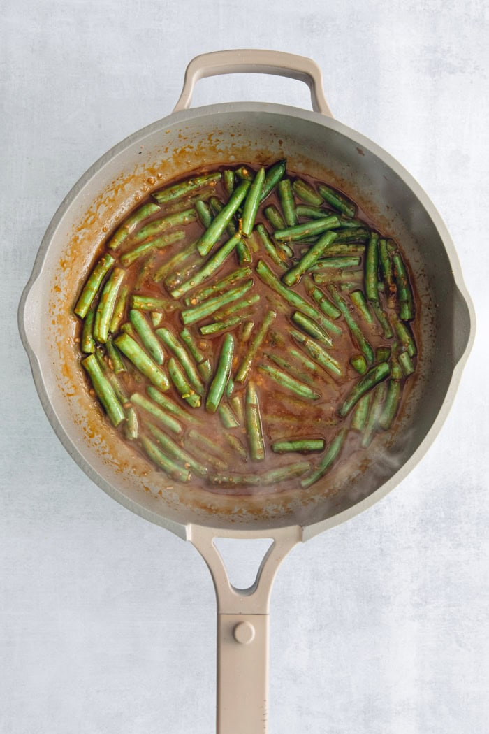 Overhead view of green beans and sauce in skillet