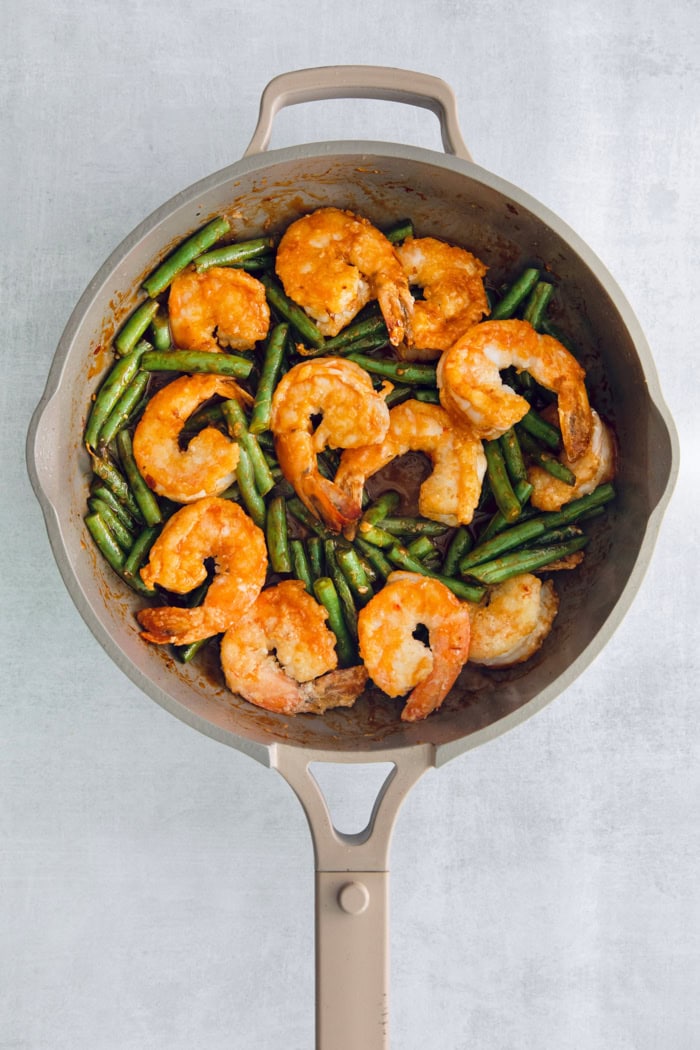 Overhead view of blistered green beans and Hunan shrimp in skillet