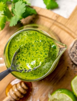 Spoonful of cilantro lime vinaigrette held over small glass pitcher