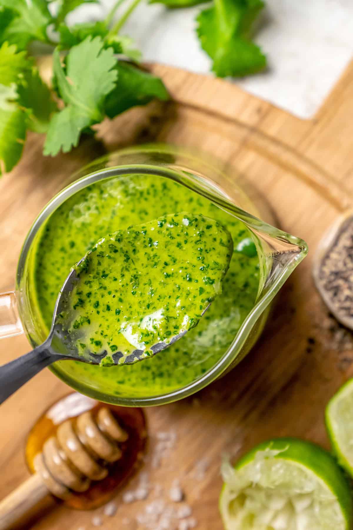 Spoonful of cilantro lime vinaigrette held over small glass pitcher
