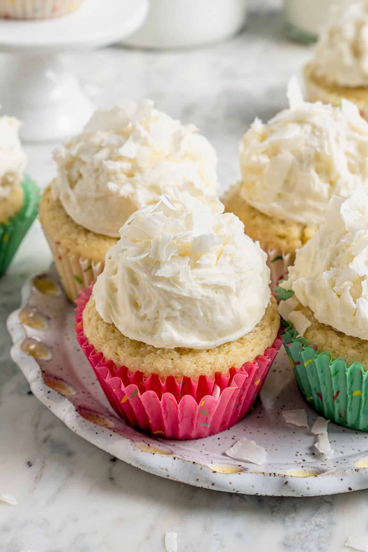coconut cupcakes with mounds of fluffy coconut frosting, in pastel cupcake liners