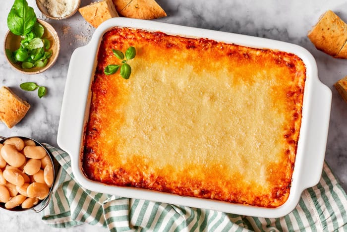 a white casserole dish of baked lasagna beans