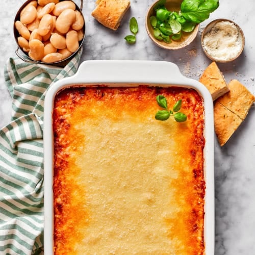 a white casserole dish of baked lasagna beans