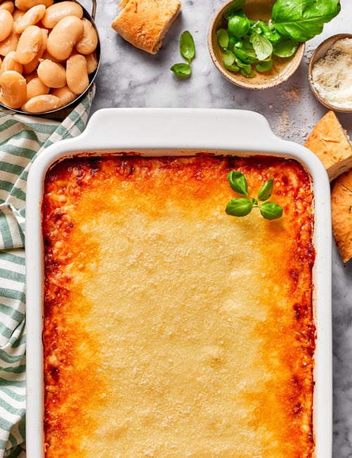 a white casserole dish of baked lasagna beans