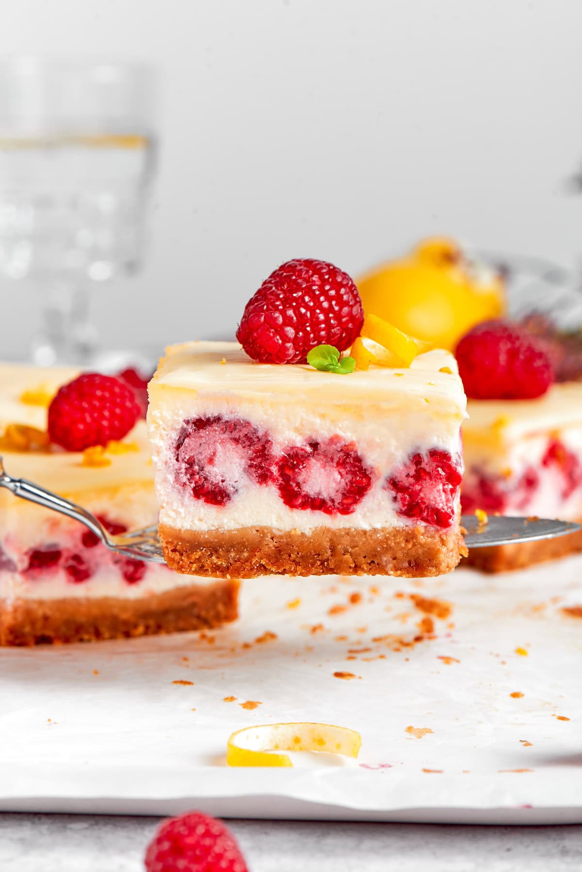 a serving spatula holding a lemon raspberry cheesecake bar