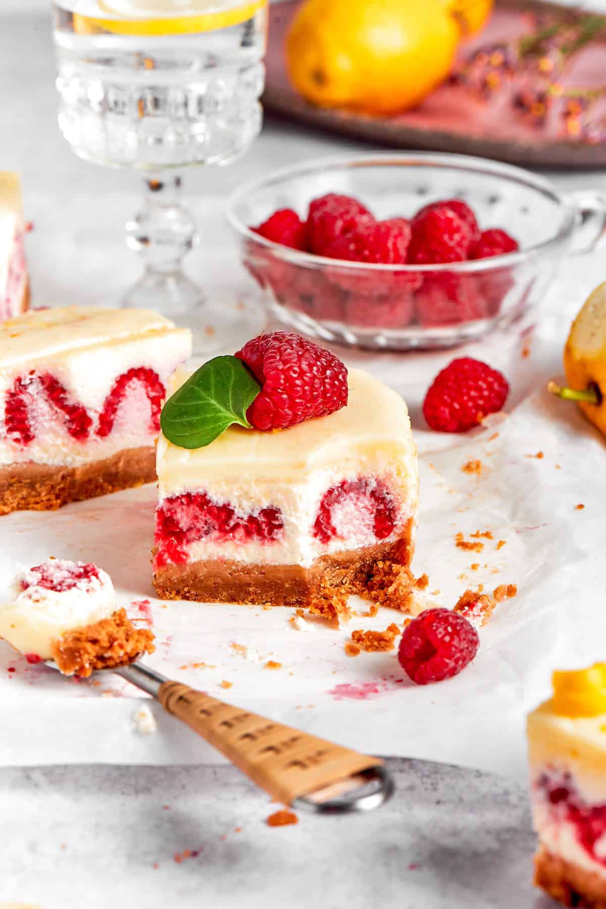 a lemon cheesecake bar with fresh raspberries, with a forkful removed