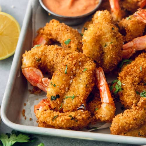 Crispy butterfly shrimp on metal tray with creamy cocktail sauce