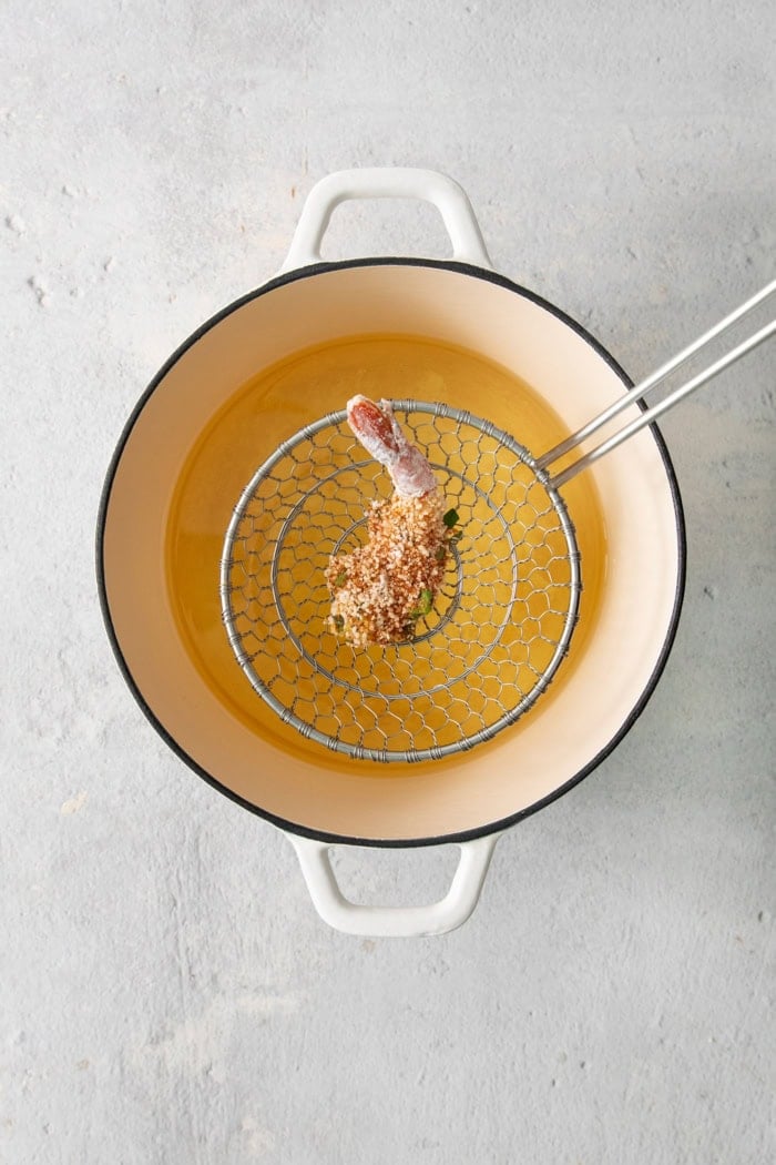 Overhead view of shrimp being dropped into pot of oil