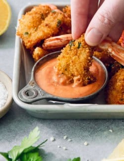 Dipping butterfly shrimp into cup of creamy cocktail sauce