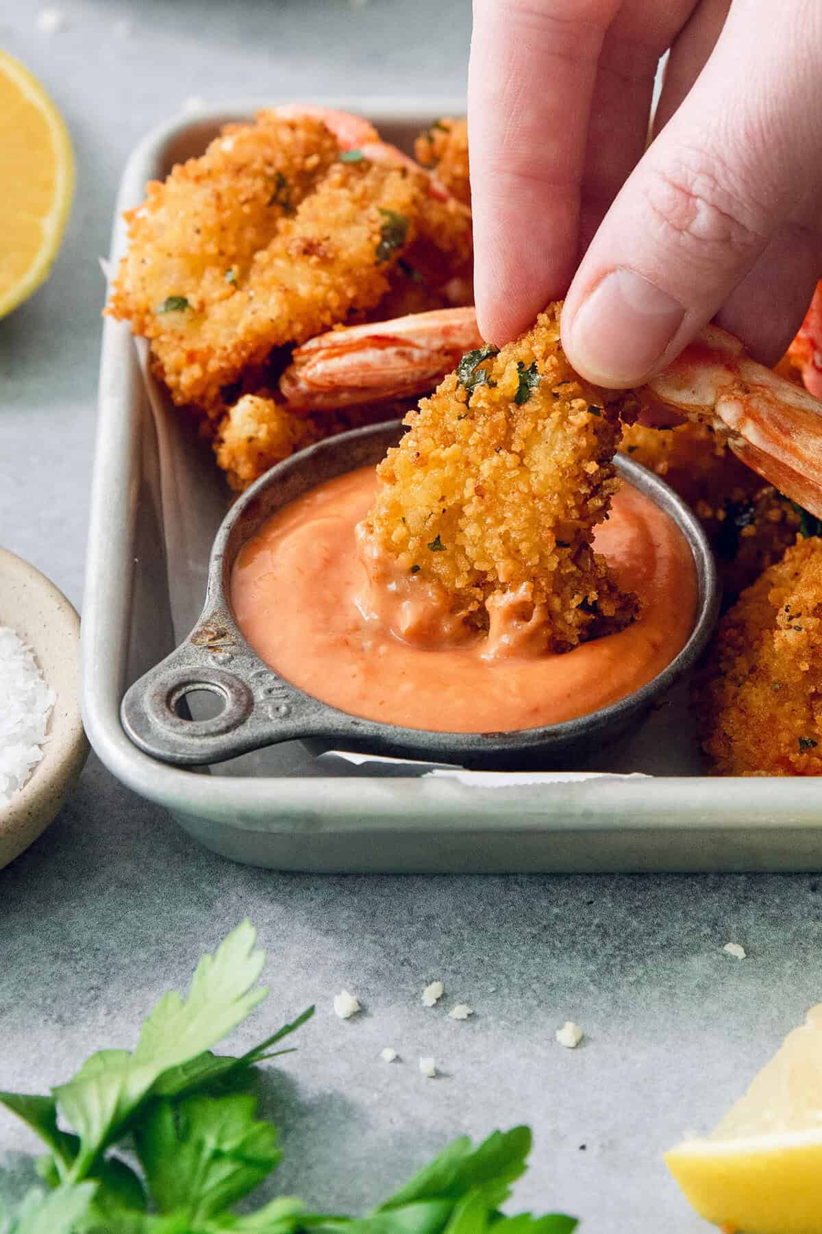 Dipping butterfly shrimp into cup of creamy cocktail sauce