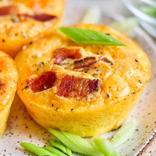 Closeup of cottage cheese egg bite on plate with green onions for garnish