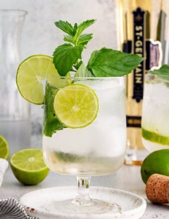 Hugo spritz cocktail in glass with sprig of mint and lime wheels