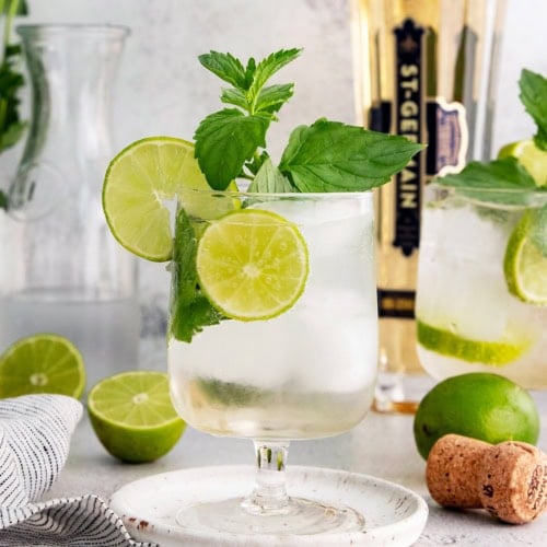Hugo spritz cocktail in glass with sprig of mint and lime wheels