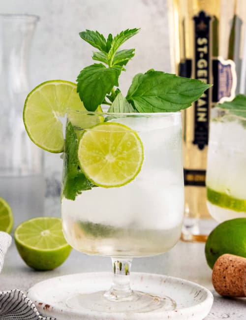Hugo spritz cocktail in glass with sprig of mint and lime wheels