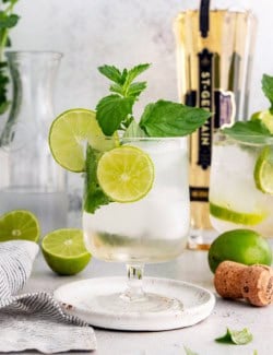Hugo spritz cocktail in glass with sprig of mint and lime wheels
