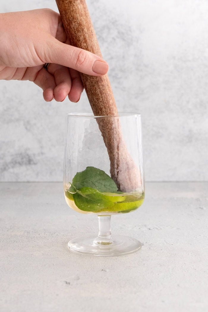Muddling lime and mint with St-Germain in glass