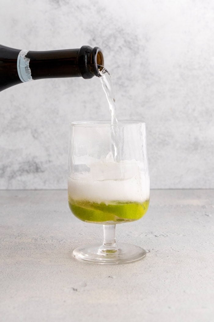 Pouring prosecco into glass for Hugo spritz cocktail