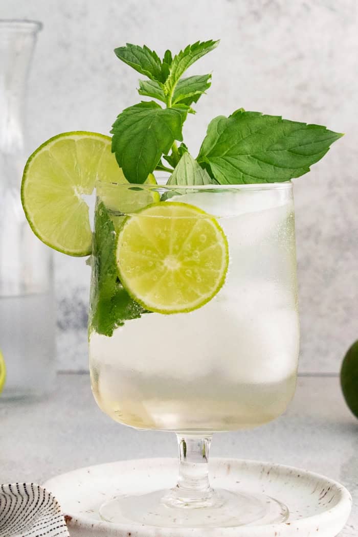 Hugo spritz cocktail in glass with lime wheels and mint sprigs
